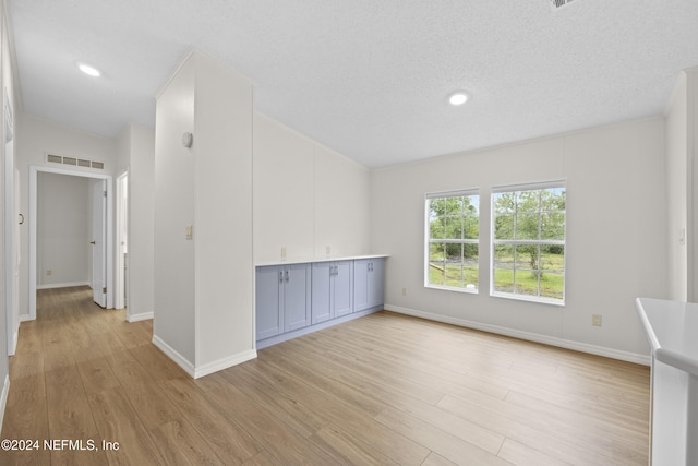 spare room with a textured ceiling and light hardwood / wood-style floors