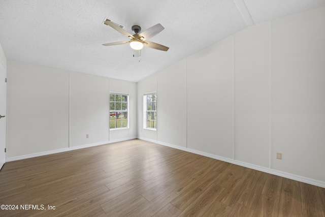 empty room featuring hardwood / wood-style floors, ceiling fan, a textured ceiling, and vaulted ceiling