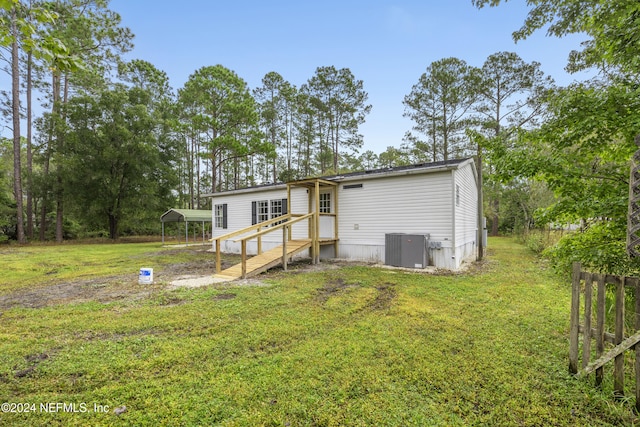 back of property featuring a carport, cooling unit, and a lawn