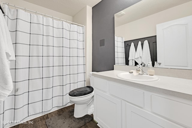 bathroom with toilet, vanity, a textured ceiling, and hardwood / wood-style flooring