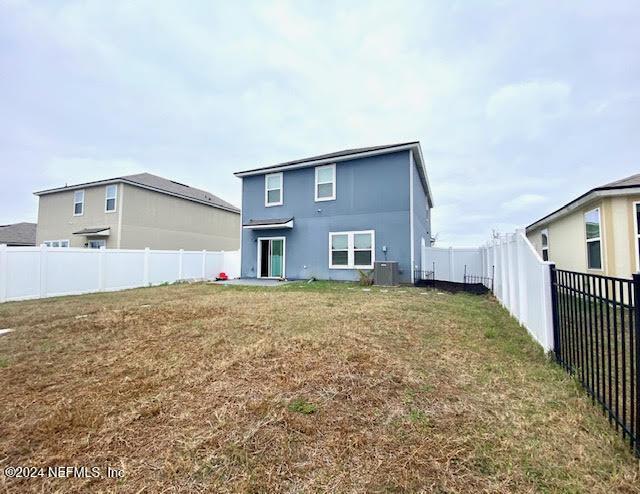 rear view of house with a lawn and central AC unit