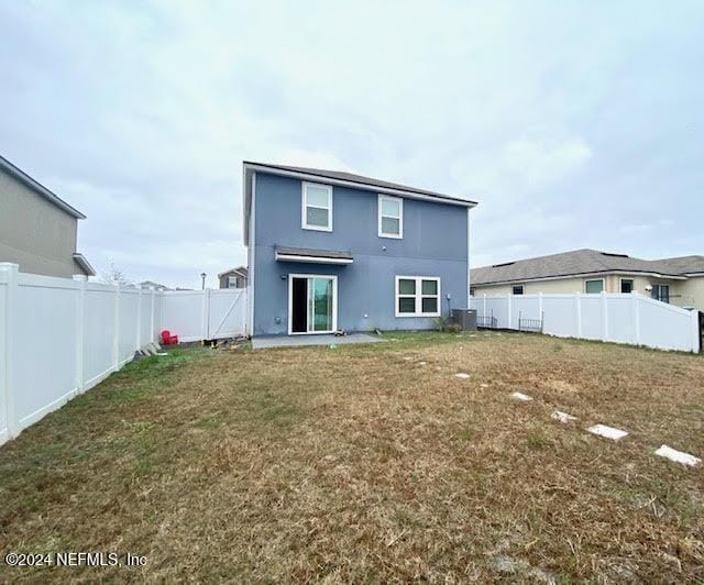 back of property with a yard and central AC unit