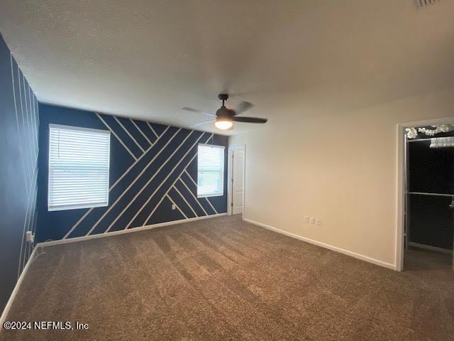 carpeted spare room featuring ceiling fan and a healthy amount of sunlight