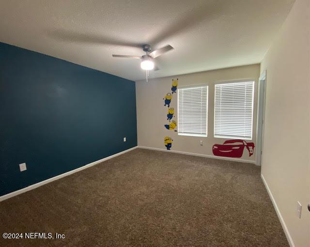 carpeted spare room featuring ceiling fan