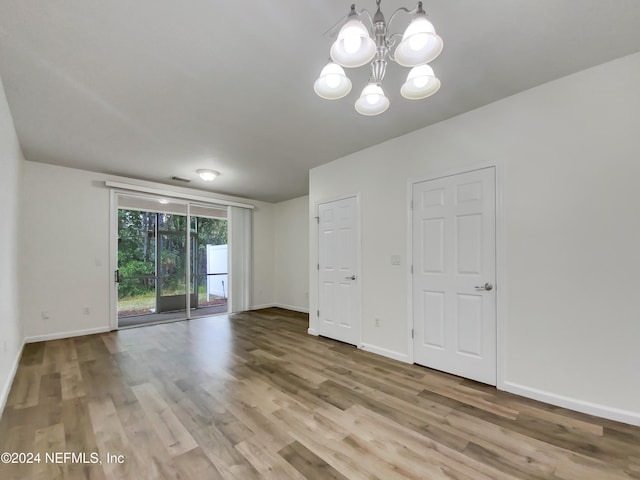 spare room featuring light hardwood / wood-style flooring and a chandelier