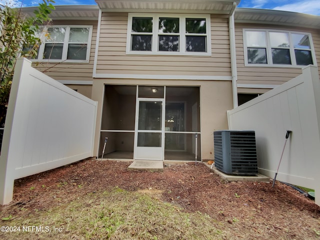 rear view of property with central AC unit and a sunroom