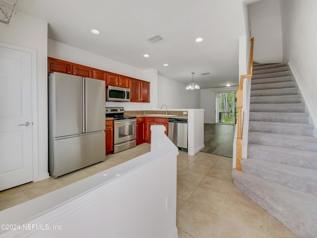 kitchen featuring sink, hanging light fixtures, an inviting chandelier, light tile patterned floors, and appliances with stainless steel finishes