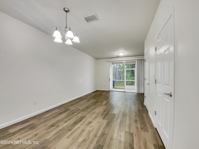 empty room featuring hardwood / wood-style flooring and an inviting chandelier