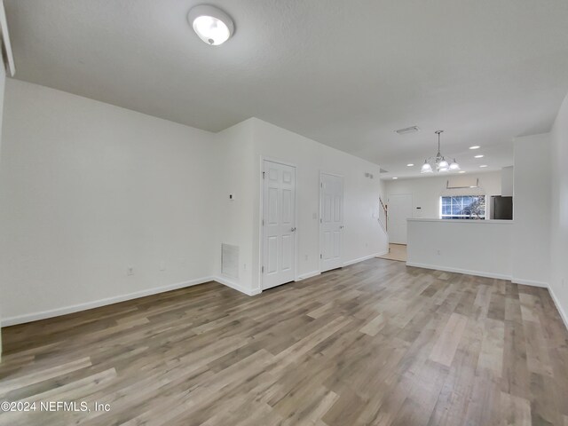 unfurnished living room with light hardwood / wood-style flooring and a chandelier