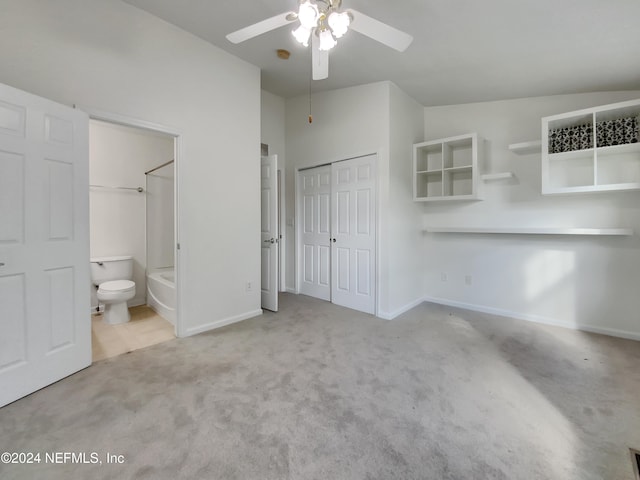 interior space featuring ceiling fan, ensuite bathroom, lofted ceiling, and light carpet