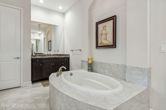 bathroom featuring vanity and a relaxing tiled tub