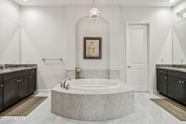 bathroom featuring a relaxing tiled tub and vanity