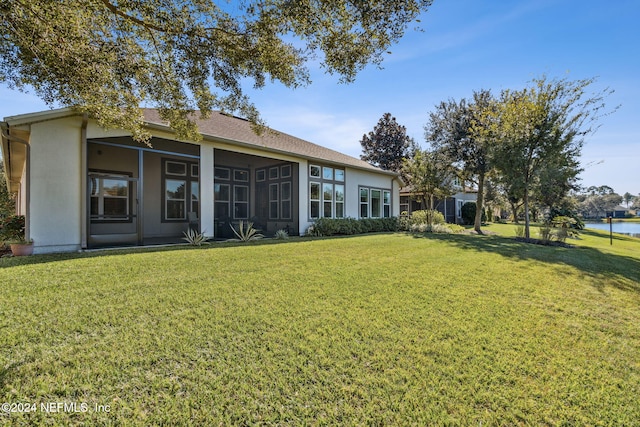 back of house featuring a yard, a water view, and a sunroom