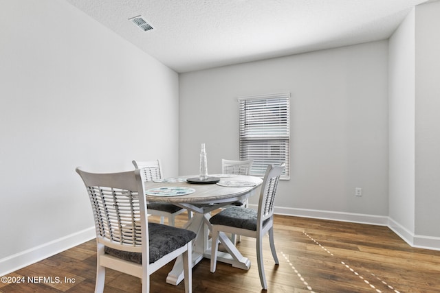 dining room with dark hardwood / wood-style floors and a textured ceiling