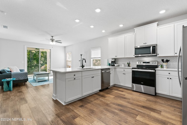 kitchen with appliances with stainless steel finishes, dark hardwood / wood-style flooring, ceiling fan, sink, and white cabinetry