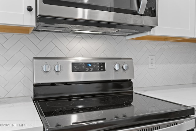 room details featuring light stone countertops, decorative backsplash, white cabinetry, and stainless steel appliances