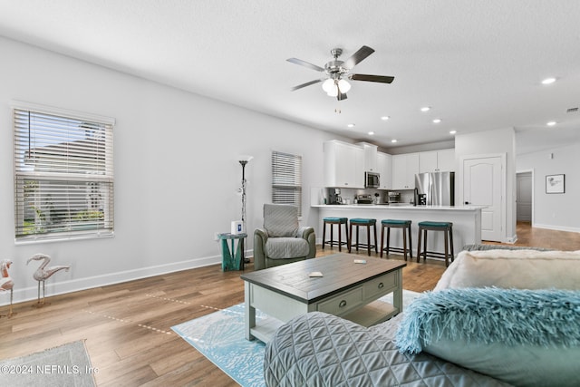 living room featuring a textured ceiling, light hardwood / wood-style floors, and ceiling fan