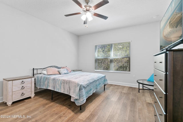 bedroom featuring ceiling fan, a textured ceiling, and light wood-type flooring