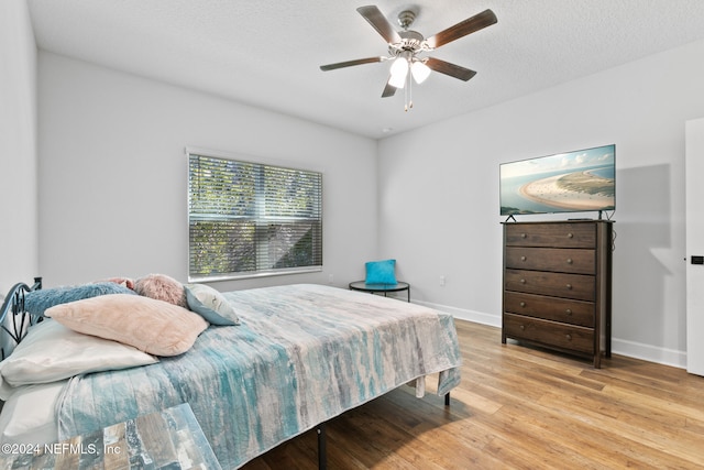 bedroom featuring a textured ceiling, light wood-type flooring, and ceiling fan