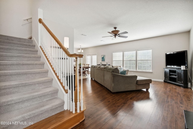 living room featuring dark wood-type flooring and ceiling fan with notable chandelier