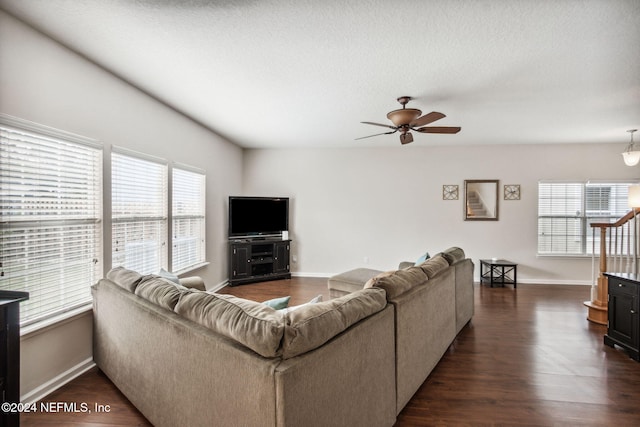 living room with a textured ceiling, ceiling fan, and dark hardwood / wood-style floors