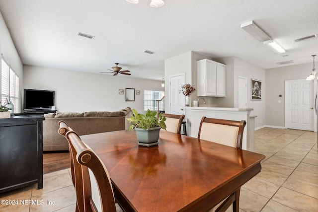 dining room featuring ceiling fan with notable chandelier, light tile patterned floors, and a textured ceiling