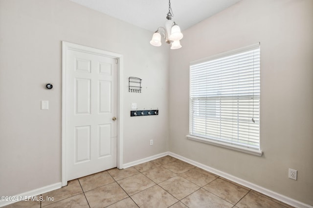 tiled empty room featuring a chandelier