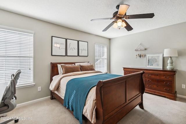 bedroom featuring ceiling fan, light colored carpet, and a textured ceiling