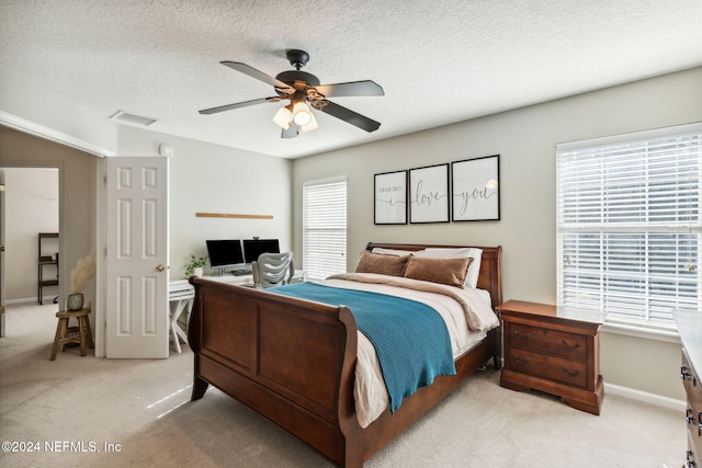 bedroom featuring ceiling fan, light colored carpet, and a textured ceiling