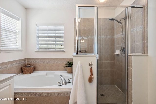 bathroom featuring plus walk in shower, vanity, and a wealth of natural light