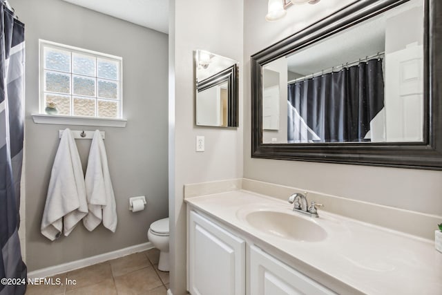 bathroom with toilet, vanity, and tile patterned floors