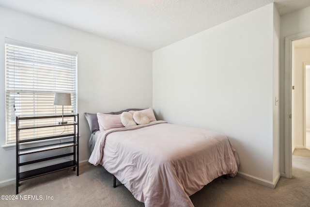 bedroom featuring light carpet and a textured ceiling