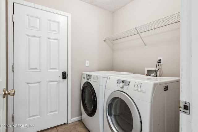 washroom featuring light tile patterned floors, a textured ceiling, and washing machine and clothes dryer