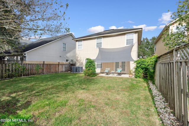 rear view of house with central AC unit and a yard