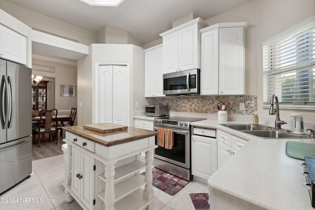 kitchen featuring tasteful backsplash, stainless steel appliances, sink, light tile patterned floors, and white cabinets