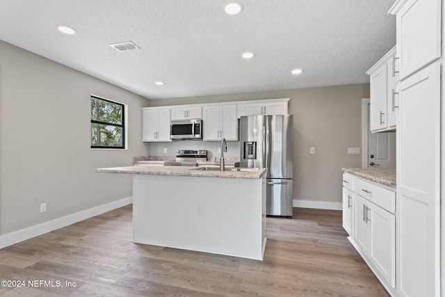 kitchen with white cabinets, appliances with stainless steel finishes, and a kitchen island with sink