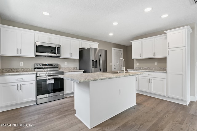 kitchen featuring white cabinets, a kitchen island with sink, sink, and appliances with stainless steel finishes