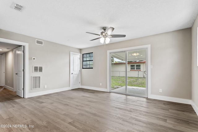 unfurnished room featuring ceiling fan, light hardwood / wood-style floors, and a textured ceiling