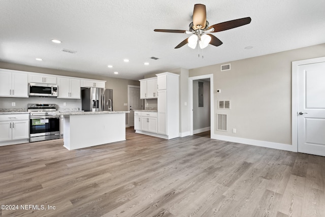 kitchen featuring stainless steel appliances, ceiling fan, a center island with sink, light hardwood / wood-style floors, and white cabinetry