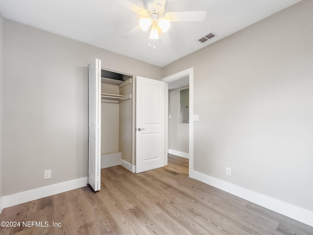 unfurnished bedroom featuring electric panel, ceiling fan, a closet, and light hardwood / wood-style floors