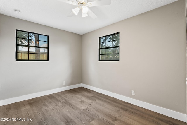 spare room with ceiling fan, a healthy amount of sunlight, and wood-type flooring