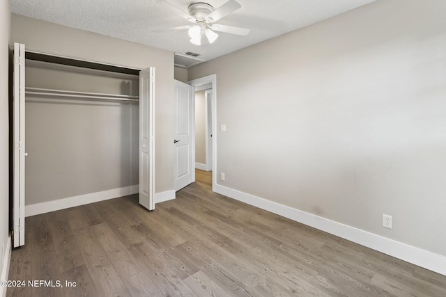 unfurnished bedroom featuring a closet, ceiling fan, hardwood / wood-style floors, and a textured ceiling