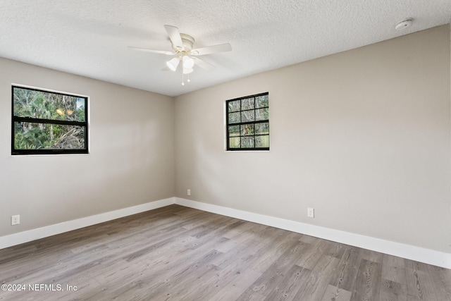 spare room with a textured ceiling, light hardwood / wood-style flooring, ceiling fan, and a healthy amount of sunlight