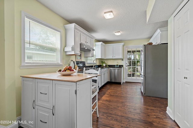 kitchen featuring sink, white cabinets, stainless steel appliances, dark wood-type flooring, and a textured ceiling