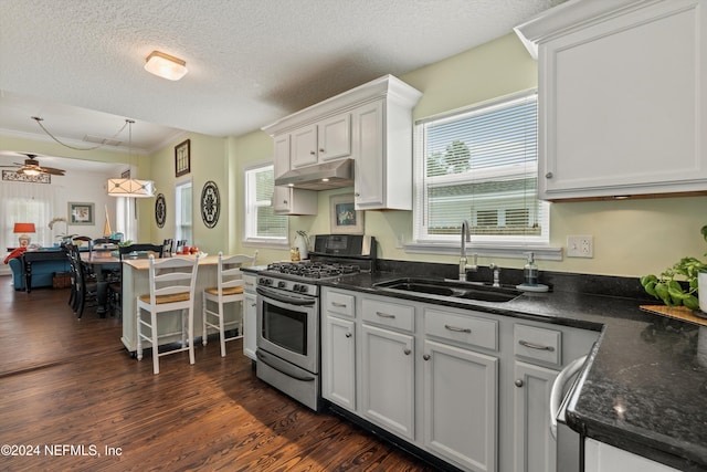 kitchen with sink, hanging light fixtures, a textured ceiling, stainless steel range with gas stovetop, and white cabinets