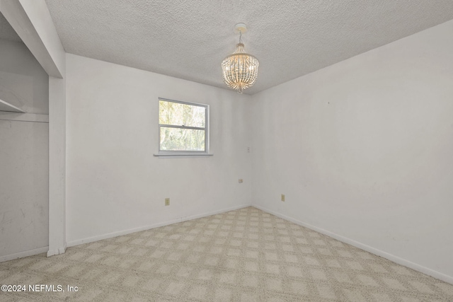 unfurnished bedroom with light colored carpet, a textured ceiling, and an inviting chandelier