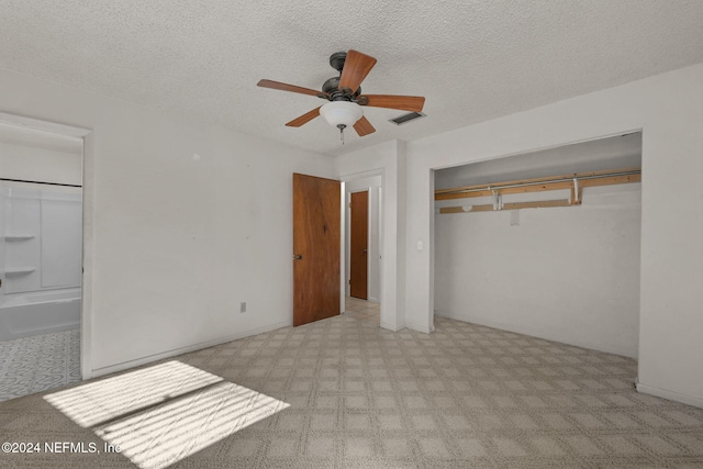 unfurnished bedroom with ceiling fan, ensuite bath, a closet, and a textured ceiling