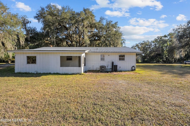 back of property with central AC unit and a lawn