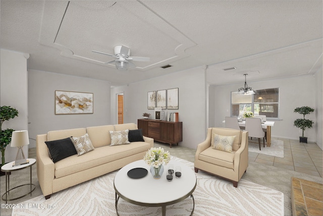 living room with light tile patterned flooring, ceiling fan with notable chandelier, and a textured ceiling