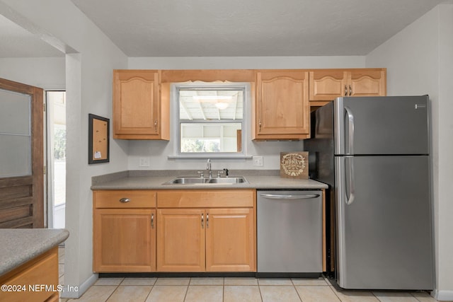 kitchen with light brown cabinetry, sink, light tile patterned floors, and stainless steel appliances